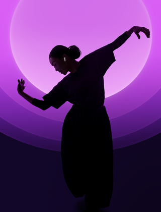 Iemand die danst met AirPods 5 in, tegen een veelkleurige achtergrond